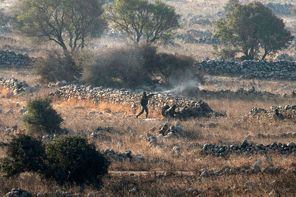 Syrian army soldiers fire during a battle with rebels near the border fence with the Israeli-occupied Golan Heights