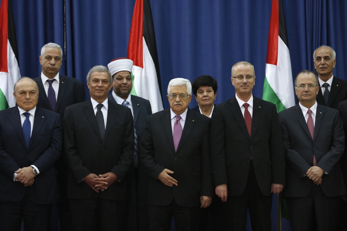 Palestinian Prime Minister Rami Hamdallah (4th L) and Palestinian President Mahmoud Abbas (3rd L) pose for a group photo with Palestinian ministers during a swearing-in ceremony of the unity government, in the West Bank city of Ramallah