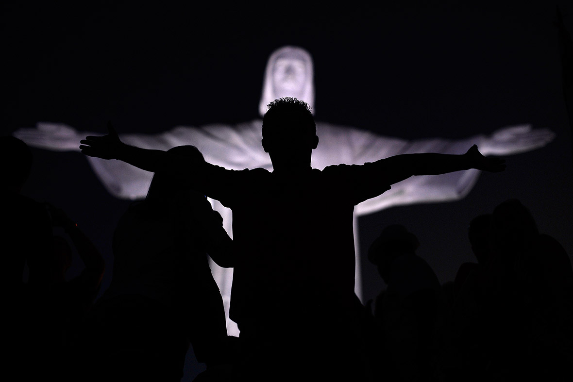 A child poses for a family picture in front of the statue of Christ the Redeemer in Rio de Janeiro