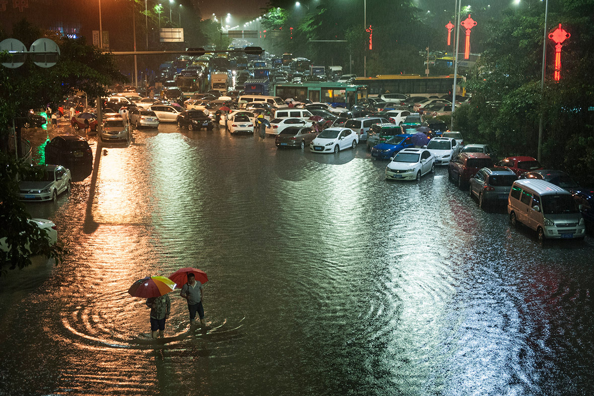 People walk along a flooded street after torrential rainfall in Shenzhen, Guangdong province,China