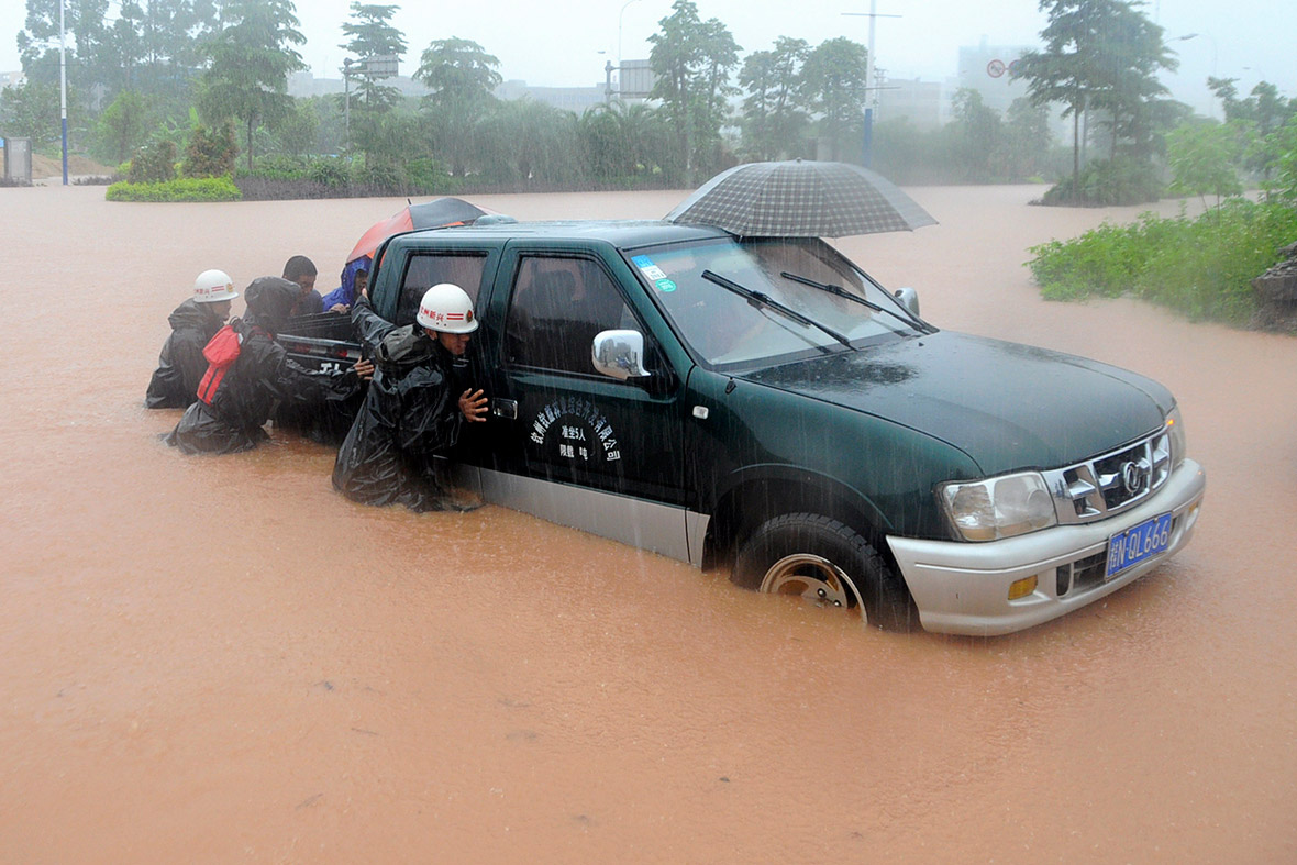 Rescue workers push a vehicle on a flooded street in Qinzhou, Guangxi Zhuang Autonomous Region, China