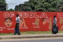 Pedestrians walk past a mural showing the symptoms of the Ebola virus in Monrovia