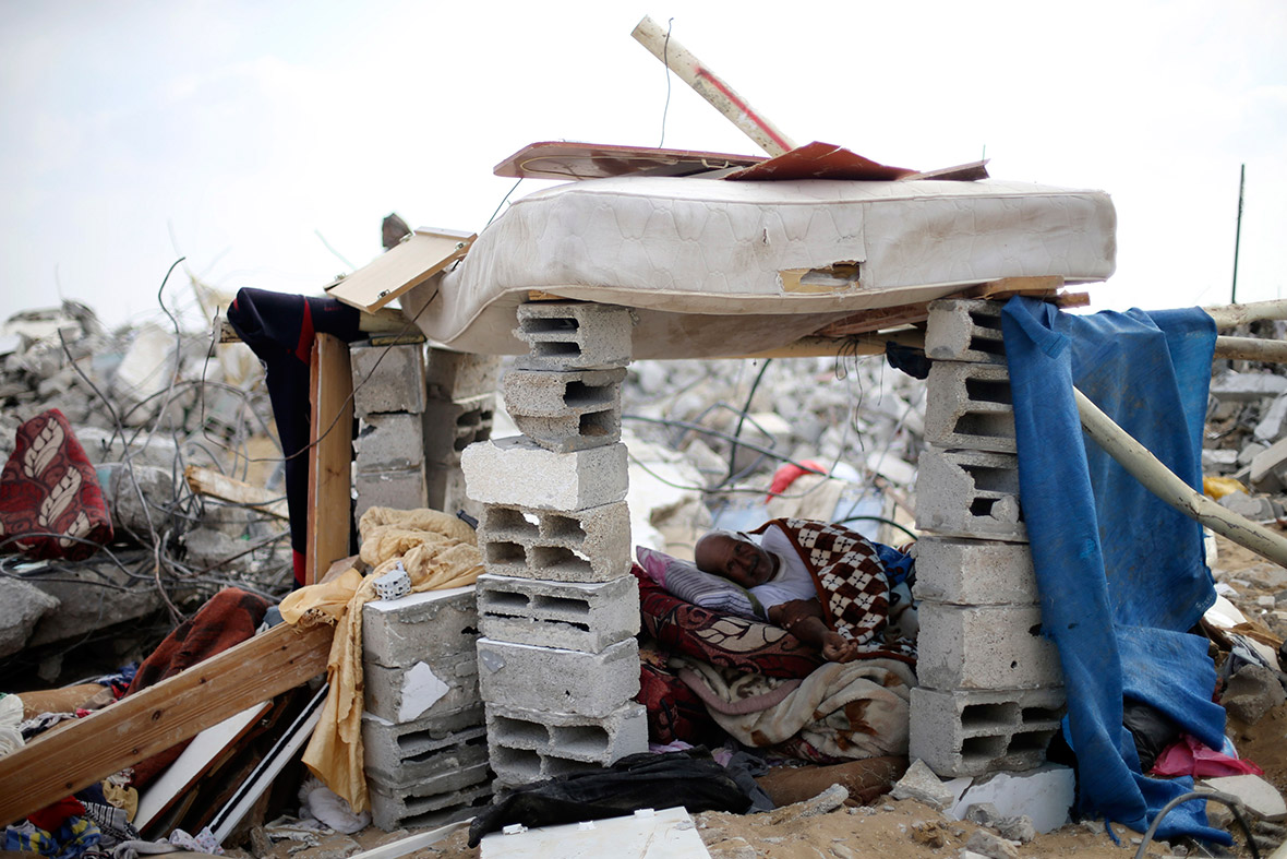 A Palestinian man rests inside a makeshift shelter next to the remains of his house, which witnesses said was destroyed in the Israeli offensive, in Khan Younis