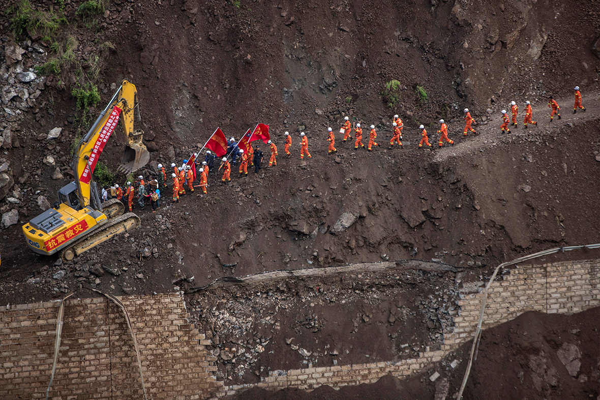 Rescue workers walk along a collapsed road at an earthquake-hit area in Ludian county