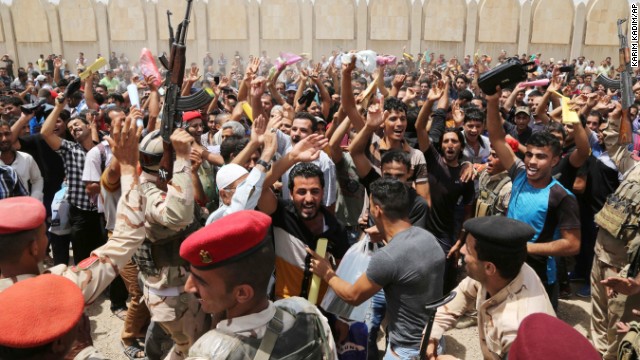Iraqi men chant slogans outside of an army recruiting center to volunteer for military service June 12 in Baghdad.