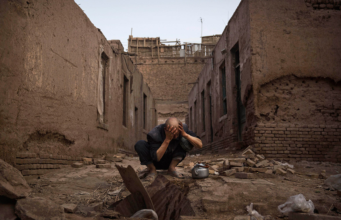 A man washes himself before prayers outside abandoned traditional houses set to be demolished to make way for new homes