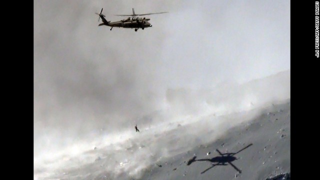 A helicopter lifts a survivor from the volcanic ash-covered top of Mount Ontake.