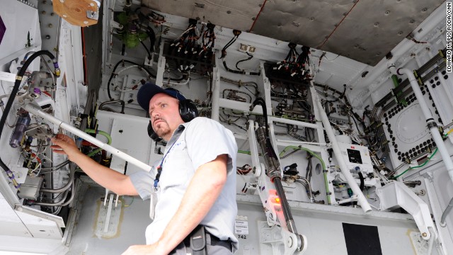 A United Airlines maintenance worker examines a hydraulic line. 