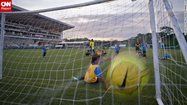 A ball <a href='http://ift.tt/1m4SIIs'>flies into the net</a> during a youth training session in Singapore. "Parents hide in the shade while kids run around for hours. Hard to understand how can they take so much sun. They must be crazy about football," said Catanescu. 