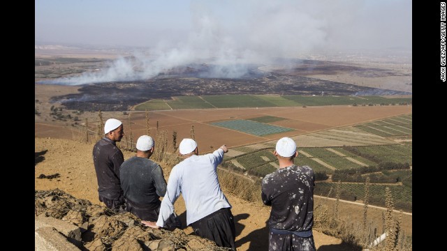 Druze men watch from the Golan Heights side of the Quneitra border with Syria as smoke rises during fighting between rebels and forces loyal to al-Assad on Wednesday, August 27. 