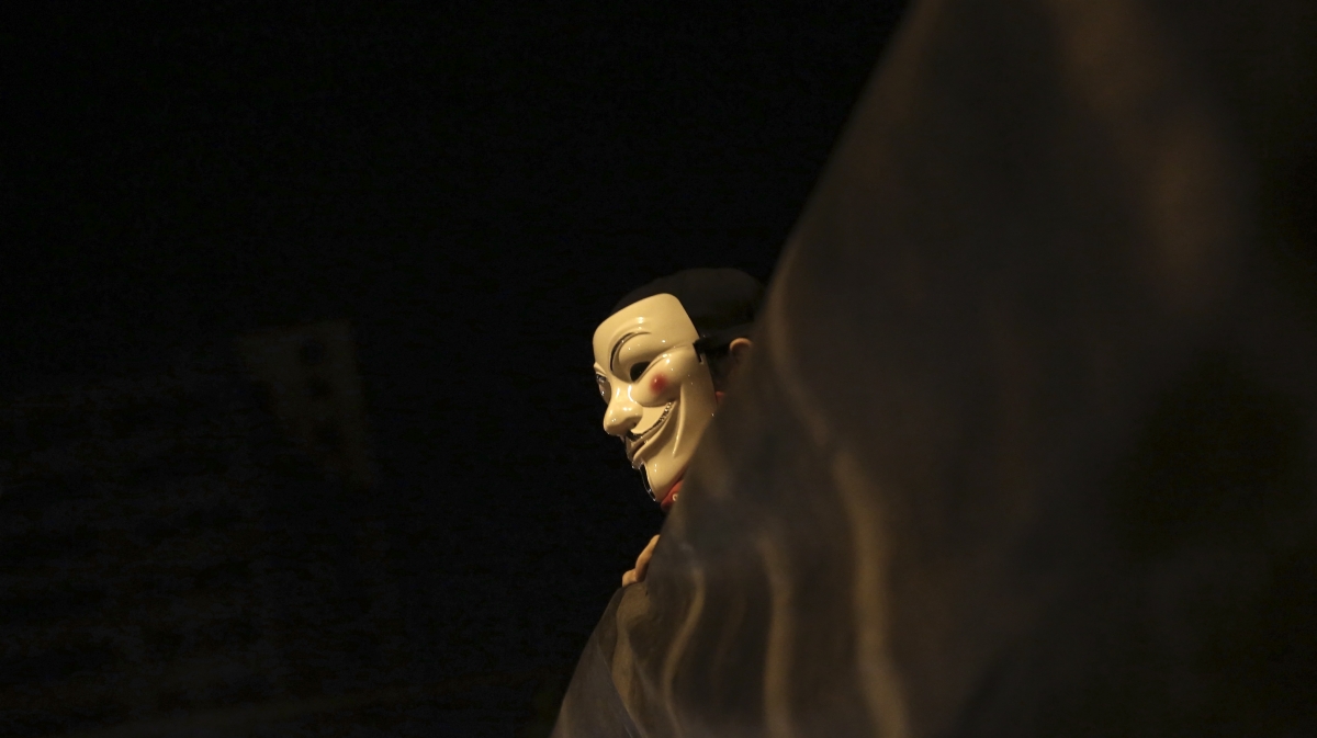 A demonstrator of the group called Black Bloc wears an anonymous mask as he holds a banner during a protest in Sao Paulo