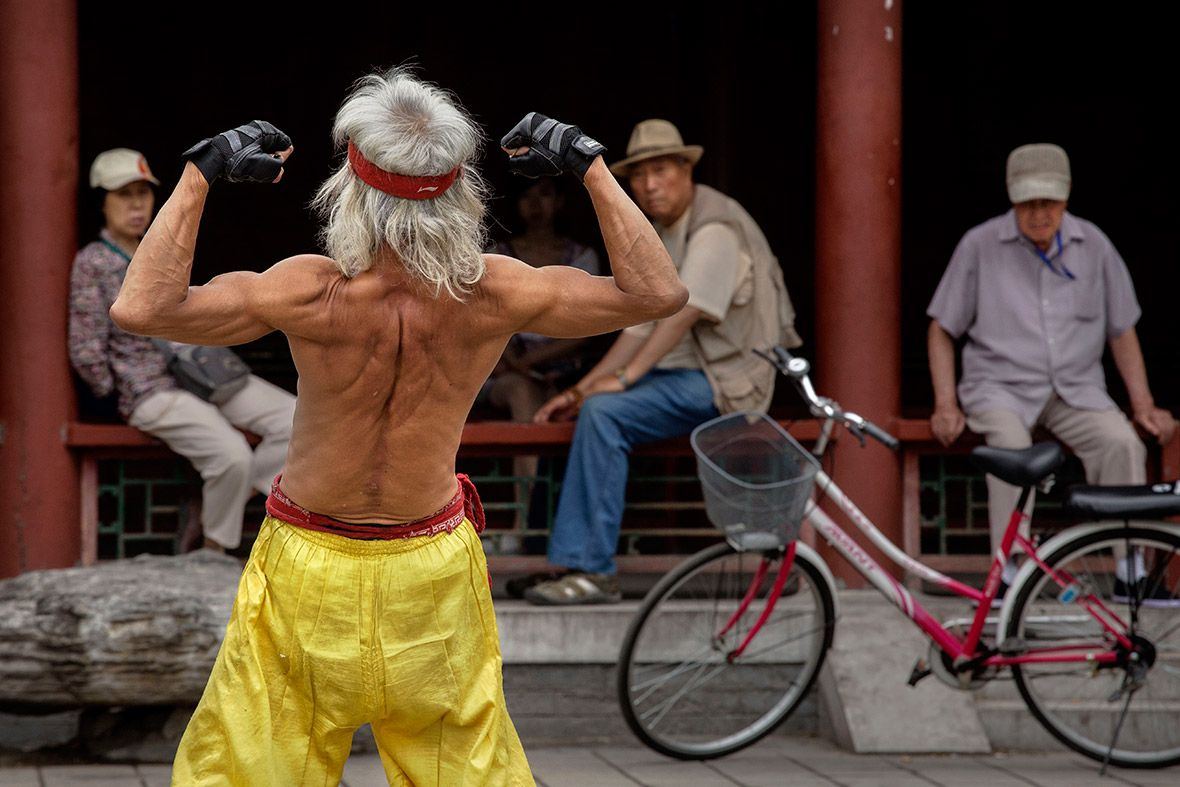 An elderly Chinese man flexes his muscles as he performs a martial arts routine on the street in Beijing