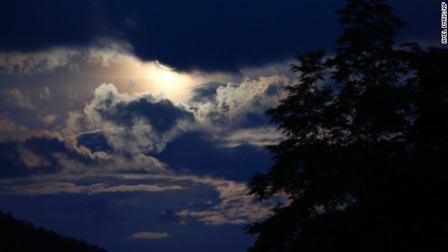 The moon casts a glow on clouds over a forest near Sarajevo.