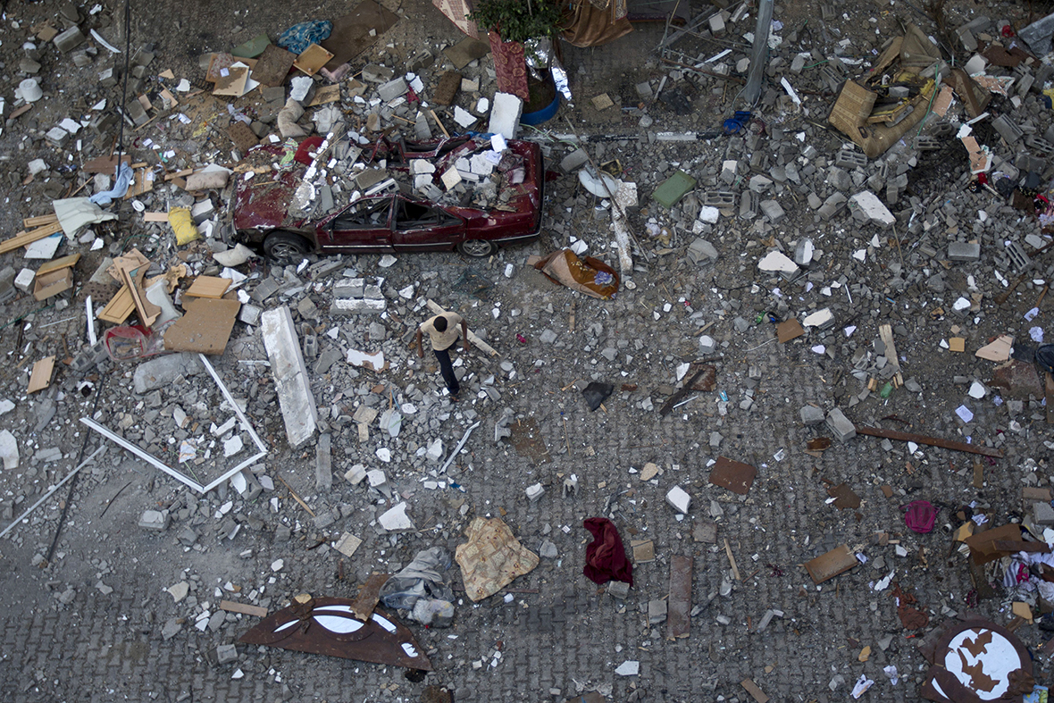A Palestinian man walks through debris as he inspects damage following an Israeli air strike in Gaza City