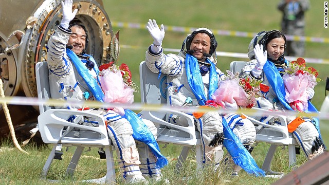 Astronauts wave after getting out from the return capsule of the Shenzhou-10 spacecraft after completing China's longest manned space mission on June 26, 2013.