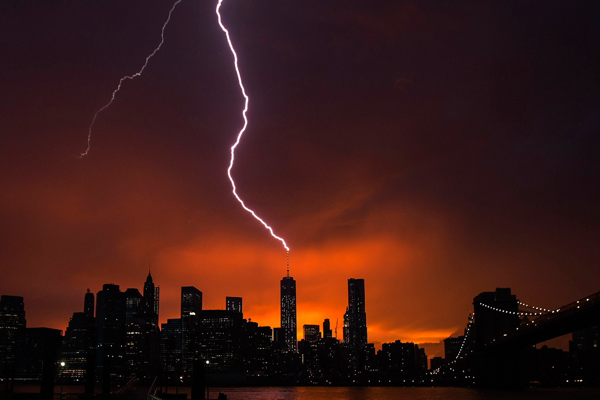 A bolt of lightning strikes One World Trade Center in Manhattan as the sun sets behind the city after a summer storm