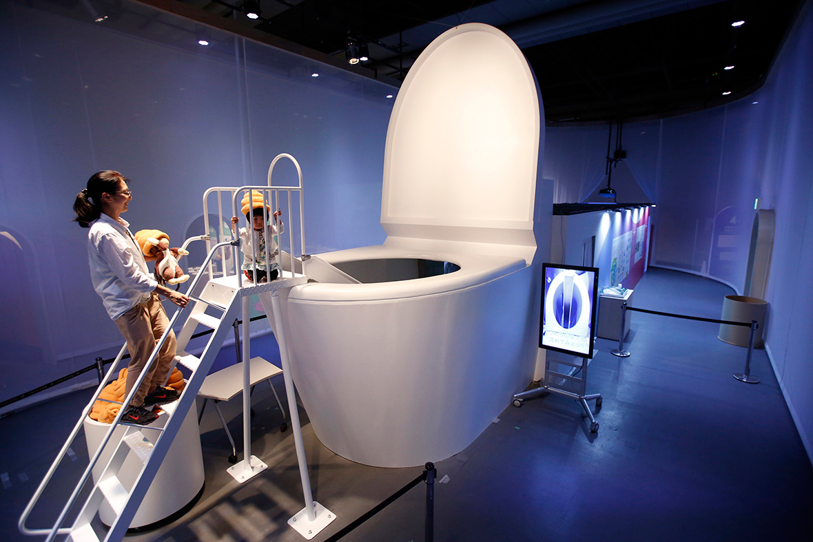 A girl wearing a faeces-shaped hat prepares to slide down into a large toilet at the Miraikan National Museum of Emerging Science and Innovation in Tokyo