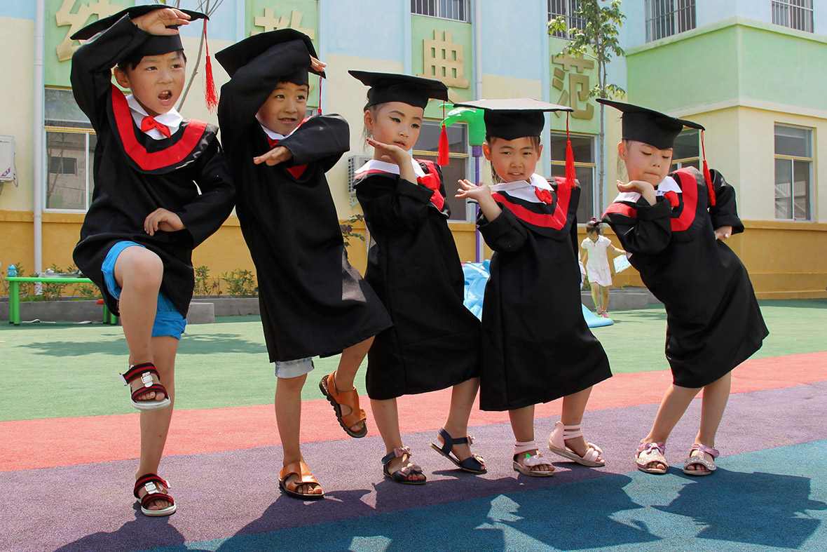 Children in gowns and mortarboards pose for pictures during their kindergarten graduation ceremony, in Wenxian county, Henan province, China