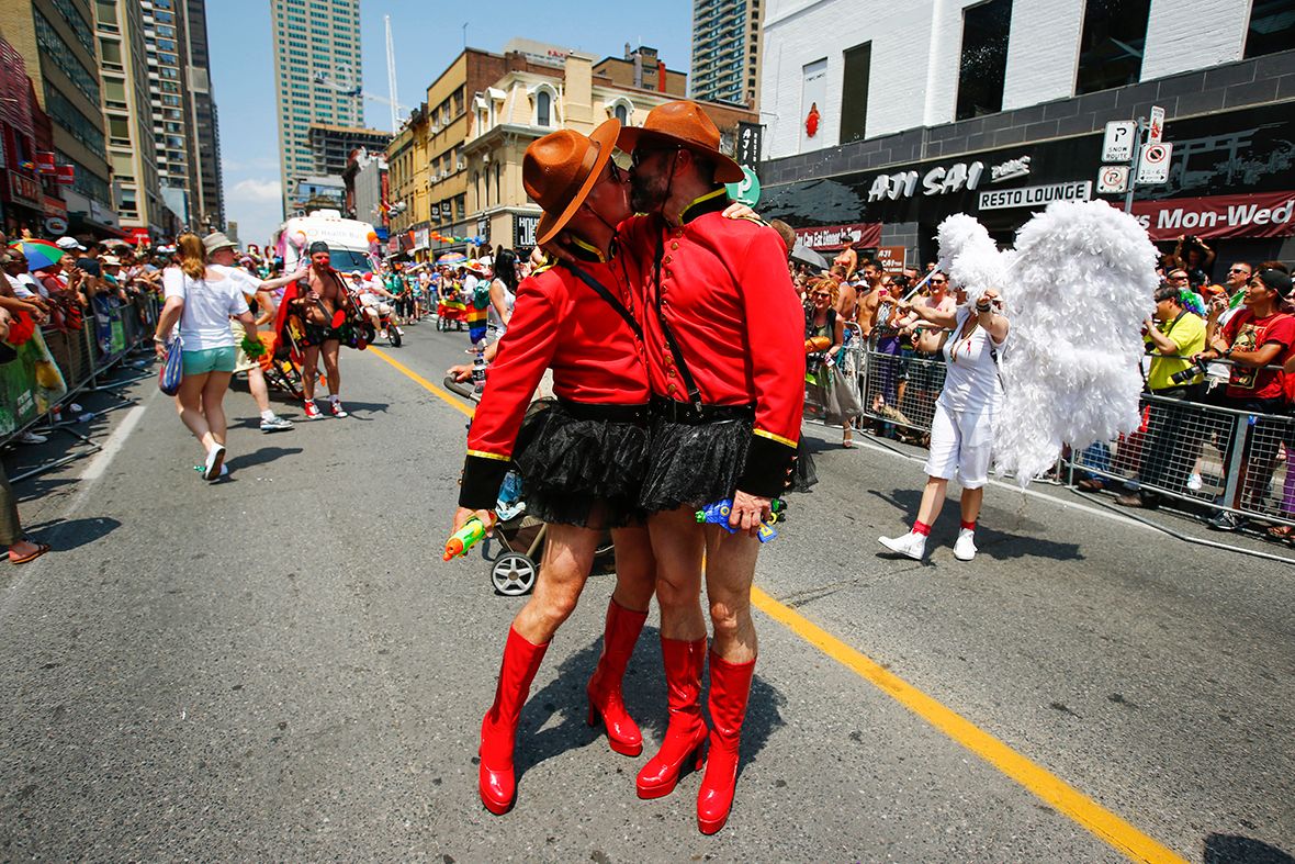 Two men dressed as Royal Canadian Mounted Police officers kiss during the WorldPride Parade in Toronto