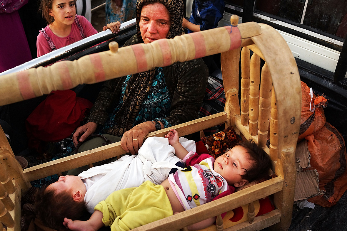 An Iraqi mother who fled fighting in the city of Tal Afar rocks her twin children in the back of a pick-up truck as they try to enter a temporary displacement camp in Khazair