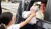 Un regalo al pasar. Sonriente, Francisco recibió flores de una niña surcoreana que fue a saludarlo antes de que dejara Seúl (AP). 
