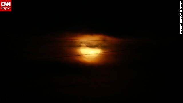 The partial eclipse <a href='http://ift.tt/1trz7Vj'>looms behind </a>wispy clouds and a string of power lines in Topeka, Kansas.