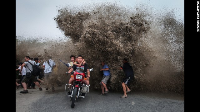 <strong>August 13:</strong> People run as a high wave hits the Qiantang River bank in Hangzhou, China.