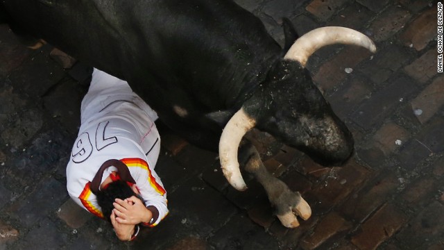 A fallen runner covers his head as a bull passes over him on July 14.