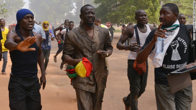 A Burkina Faso deputy clutches a national flag as he flees parliament on October 30.