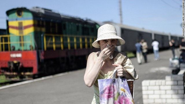 A woman covers her mouth with a piece of fabric July 20 to ward off smells from railway cars that reportedly contain passengers' bodies.