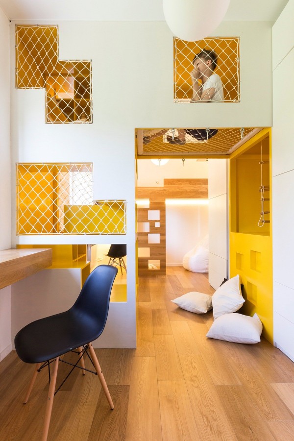 The room for the two young children is awesome beyond belief. Contained in a space less than 16-square-meters, the modular jungle gym in the middle adds considerable vertical space to play. The colorful volume separates the two sleeping areas, allowing a younger and older sibling to cohabitate in peace.
