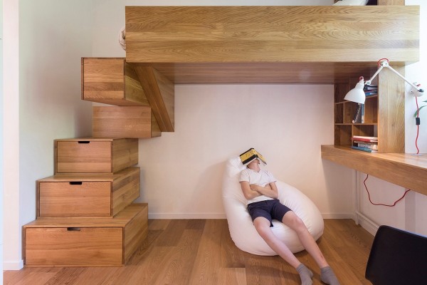 On one side of the room, a refined loft space gives the older sibling a nice place to sleep and study. Stairs made of drawers lead to the bed and bookshelves house homework supplies underneath. It has a nice mature look that contrasts well with the wild play zone.