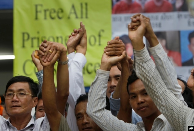 Members of the opposition Cambodia National Rescue Party raise joined hands for photographs at their party headquarters in Phnom Penh, May 27, 2016. A Cambodian court had convicted three military commandos of beating up two CNRP lawmakers outside the parliament in the previous year and had sentenced them to one year each in prison.