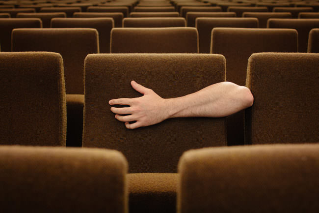 Ein Arm umarmt einen Sitz im Kino