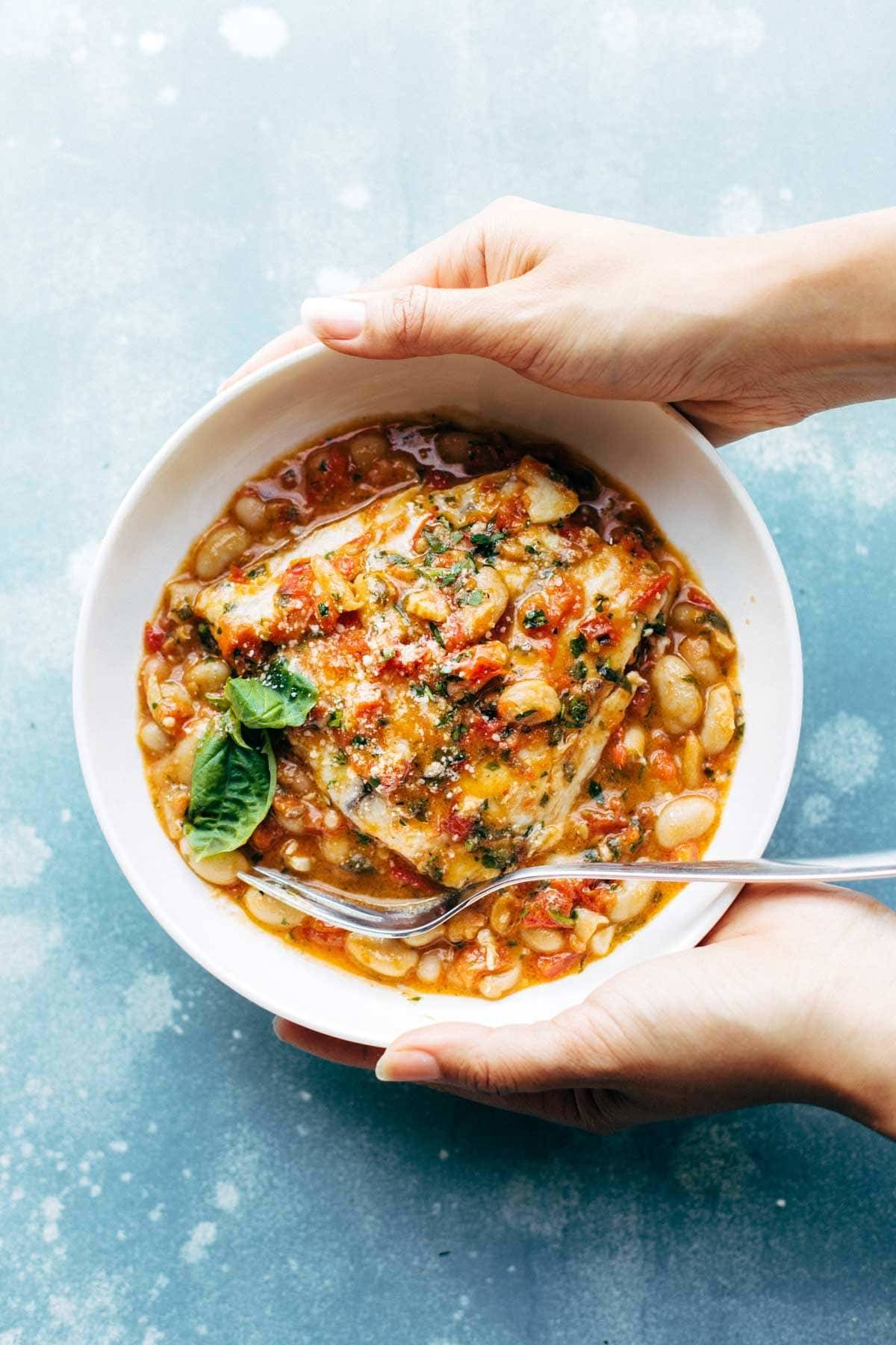 Garlic Basil Barramundi Skillet with Tomato Butter Sauce! SO YUMMY and super easy, with basic ingredients like garlic, basil, tomatoes, white beans, Parmesan, and white fish. Perfect with a green salad and crusty bread. | pinchofyum.com
