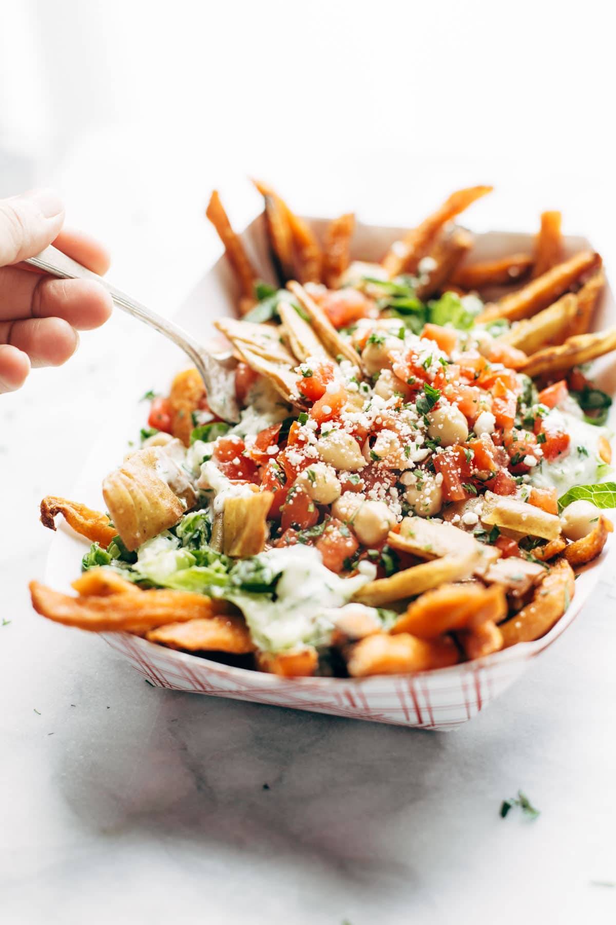 Loaded Mediterranean Street Cart Fries: sweet potato fries topped with fresh romaine, tzatziki, marinated tomatoes and chickpeas, feta cheese, and more. Meatless and mind-blowing, all in one. | pinchofyum.com