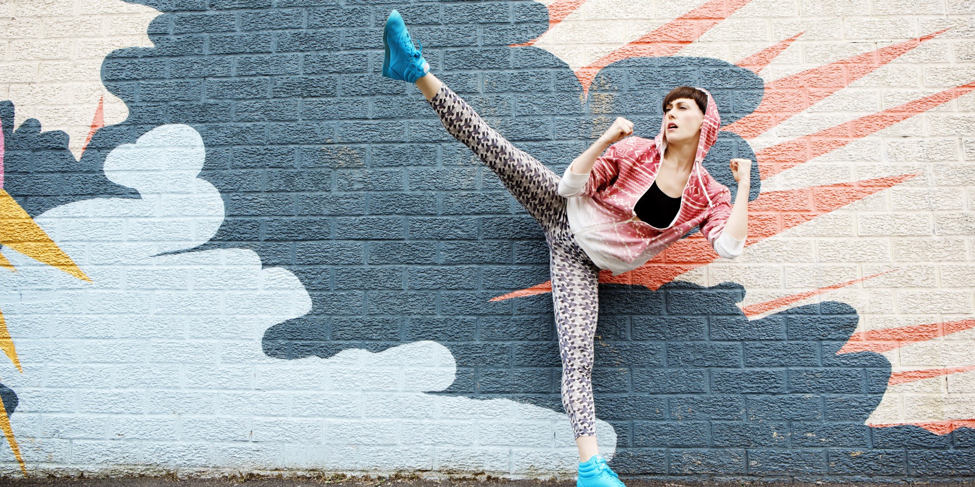 Woman Kicking Leg Up In Front of Graffiti Wall