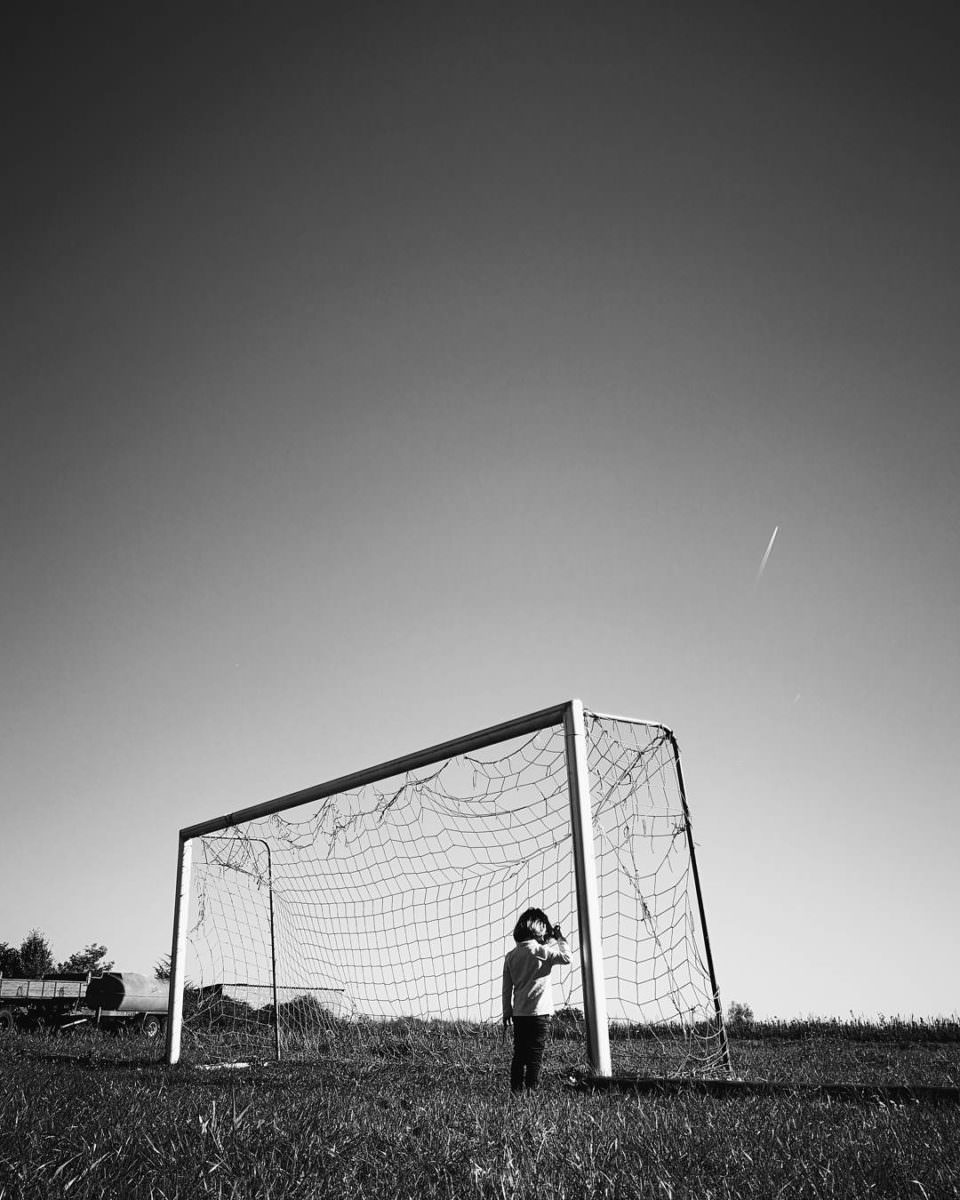 Kind in einem Fußballtor von hinten zu sehen in schwarzweiß.