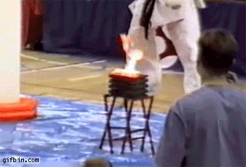 Gif guy's head catches on fire during a martial arts tournament after breaking flaming stack of bricks.