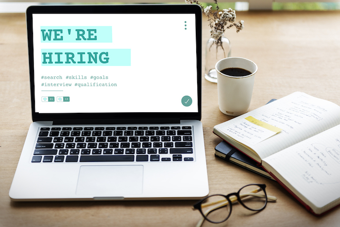 Hiring via your business website; laptop on desk with text reading "we're hiring" 