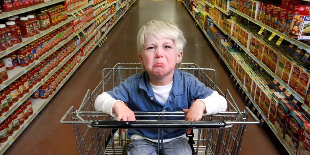 Foto niño llorando en el carro de la compra de un supermercado