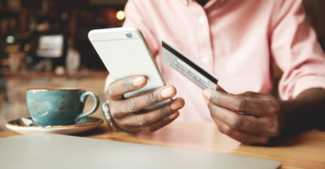 Man on cell phone holding credit card; SaaS pricing concept