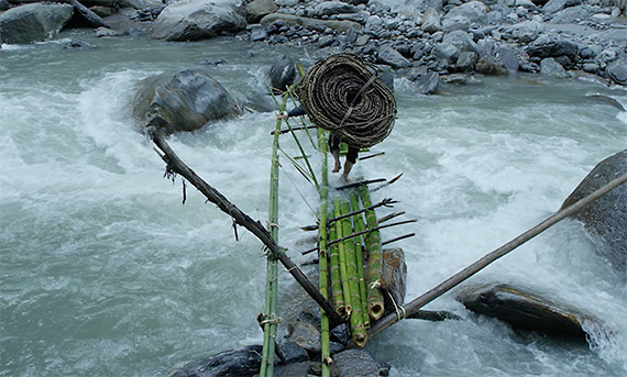 Hiking over Himalayan river with bamboo rope