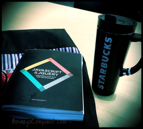 JavaScript book on red tote bag with Starbucks coffee container next to the book. 