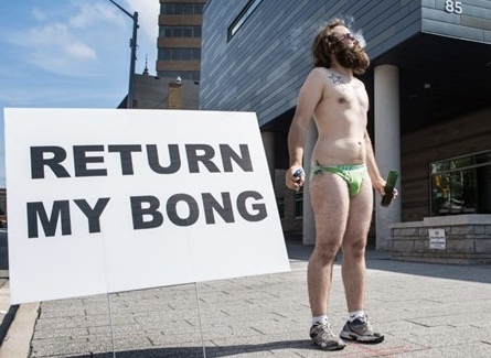 Underwear-clad man outside of courthouse with sign: "Return my bong"