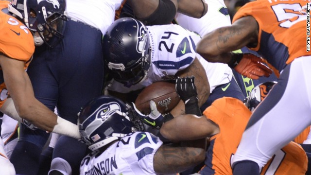 Marshawn Lynch (no 24) forces his way through a pack of players to score the opening touchdown of the game for the Seahawks.