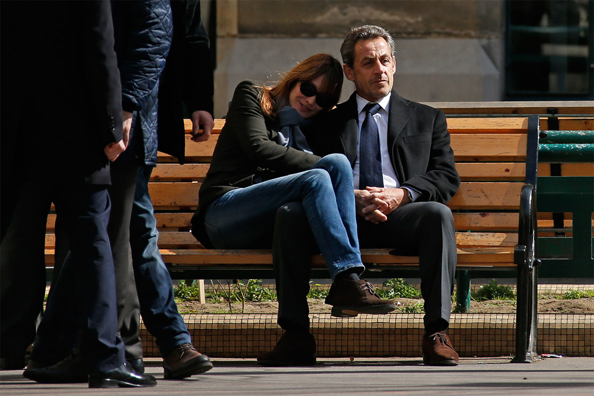 Former French President Nicolas Sarkozy sits on a bench with his wife Carla Bruni-Sarkozy after voting in the first round in the French mayoral elections in Paris
