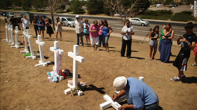 Greg Zanis writes the names of the victims of last weekend's mass shooting on the crosses before erecting them at the memorial across from the Century 16 movie theater on Sunday. Zanis, a carpenter, drove all night from Illinois to deliver the crosses.