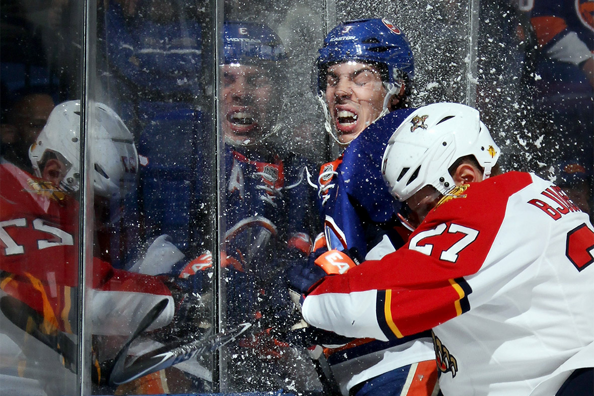 Travis Hamonic of the New York Islanders is hit by Nick Bjugstad of the Florida Panthers during their ice hockey match at the Nassau Veterans Memorial Coliseum in Uniondale, New York