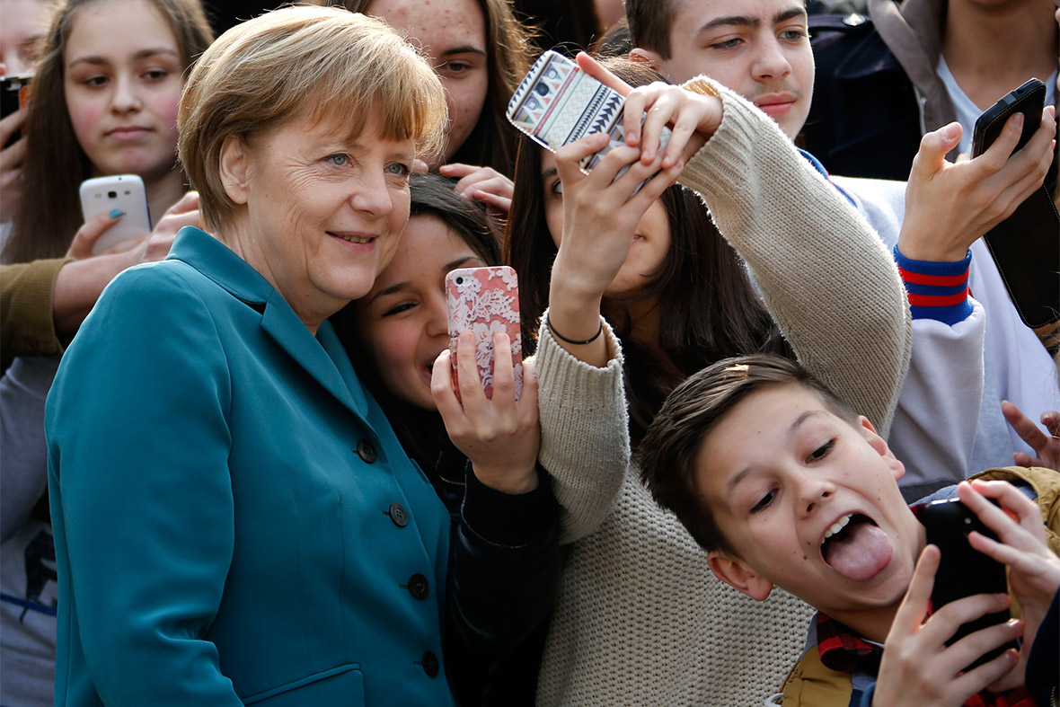 Pupils take mobile phone 'selfies' with German Chancellor Angela Merkel, as she arrives for a visit at Robert-Jungk Europe high school in Berlin